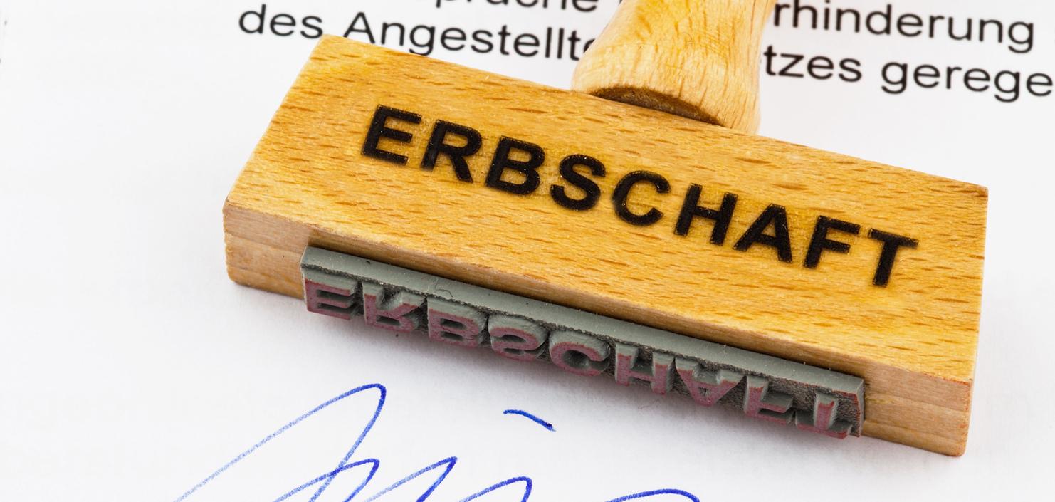 Holzstempel mit Aufschrift "ERBSCHAFT" auf einem Dokument, das eine Unterschrift und den Stempelabdruck zeigt.
